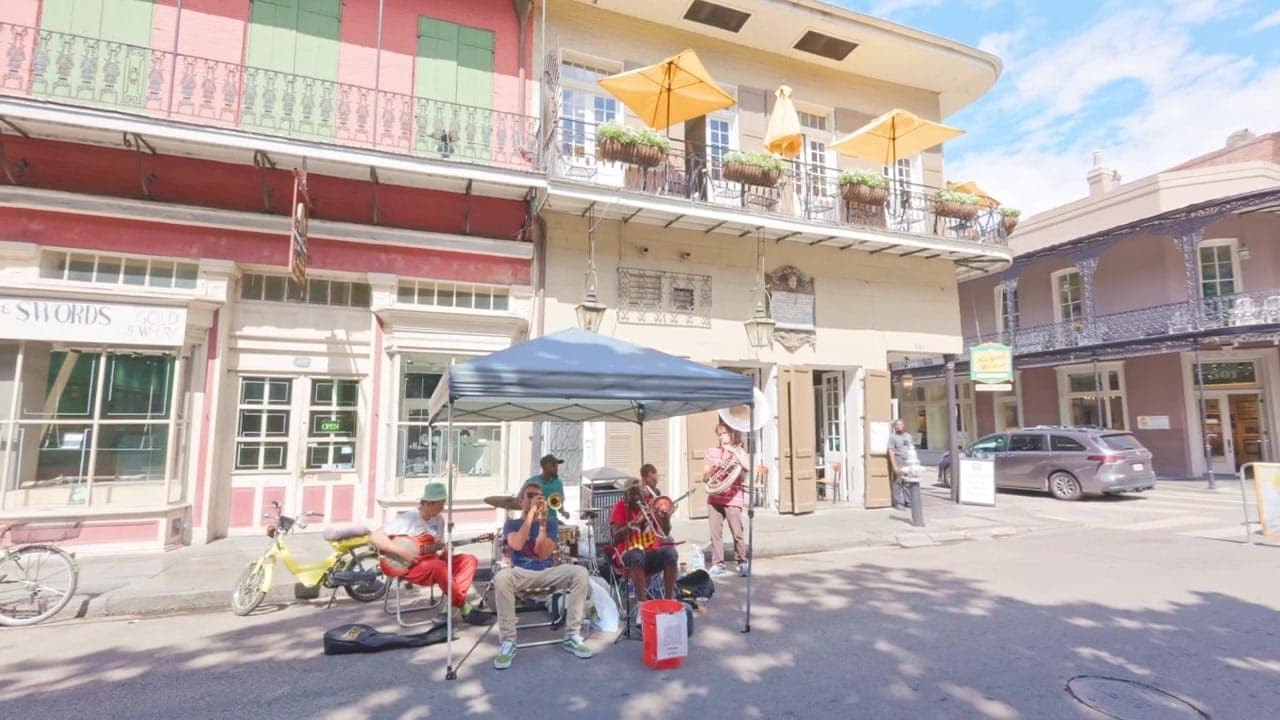 Creole townhouses with cast-iron balconies and shuttered openings along a Quarter street.